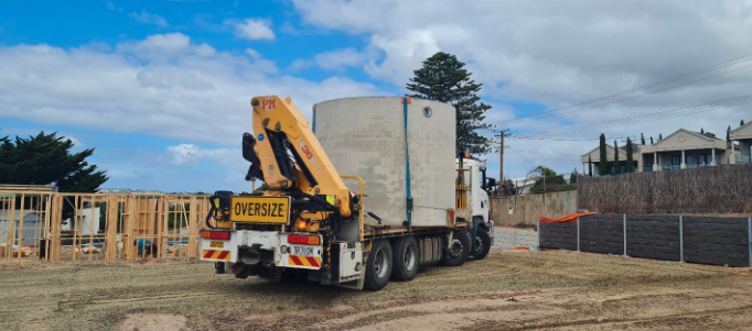 Image shows a Ri-Indusrtires concrete rainwater tank being delivered to a job site.